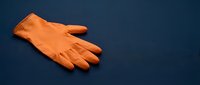 Pair of bright orange latex cleaning gloves isolated on dark blue background, ready for household chores, sanitation work, or safety protection purposes.