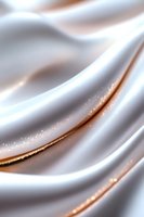Elegant white silk fabric with golden glitter waves creates luxurious flowing texture, soft folds catching light in smooth curves for luxury brand backgrounds.
