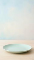 Pale green ceramic plate on wooden surface with soft neutral background, suitable for tableware, dinnerware, and kitchen product design projects.