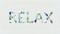 Word RELAX spelled with colorful sea glass and pebbles on white sand, evoking summer vacation, beach wellness, and coastal calm.