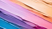 Vibrant diagonal layers of paper in pastel and bright colors create modern abstract background with textured edges and soft gradient transitions from blue to peach tones.