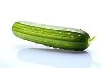 Fresh green cucumber with water drops on white background, isolated produce photo showing crisp texture and natural appearance for food and cooking concepts.