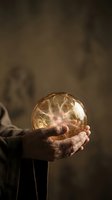Hands holding glowing plasma ball with electrical filaments inside against blurred background, representing innovation, energy, and futuristic technology concepts.