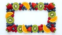 Fresh fruit frame border with strawberries, kiwi, orange slices and blueberries on white background for healthy eating and nutrition design.