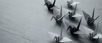 Origami paper cranes in black and white arranged on textured surface for minimalist design projects and artistic compositions.