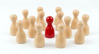 Red wooden pawn figure standing out among natural wood pawns on white background. Leadership, uniqueness and individuality concept for business presentations.