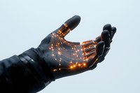 Glowing orange light trails on black robotic hand against light background showing advanced technology and artificial intelligence in motion.