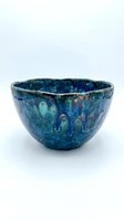 Antique ceramic bowl with deep blue glaze and iridescent patina featuring decorative relief patterns, isolated on white background for design and product use.
