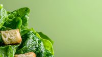 Fresh crisp romaine lettuce leaves with crunchy golden croutons on green background, water droplets glistening on leaves, macro food photography.
