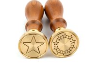 Pair of wooden-handled brass stamps with star and circular star pattern designs, isolated on white background for stamping, crafting, and decorative marking applications.