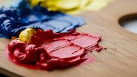 Vibrant oil paint colors mixed on wooden artist palette with paintbrush, creative art supplies for painting and artistic expression in studio workspace.