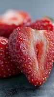 Fresh ripe strawberry macro shot showing detailed texture with water droplets on dark background. Vibrant red fruit with natural lighting for food photography.