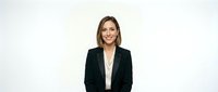 Professional young Caucasian businesswoman in black blazer smiling confidently against white background for corporate presentations and marketing materials.