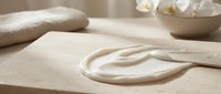 Artisan baker kneading and shaping fresh dough on wooden surface with flour and baking tools nearby, suitable for culinary, bakery, and food preparation content.