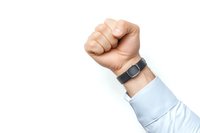 Raised fist of Caucasian businessman wearing fitness tracker and light blue shirt sleeve, symbolizing determination, success and power in corporate environment.