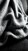 Crumpled gray linen fabric with textured weave in monochrome, showcasing natural folds and shadows for textile, fashion, and interior design projects.