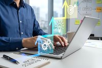 Business professional working on laptop with digital innovation icons and strategic planning elements in modern office environment.
