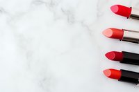 Red lipsticks arranged diagonally on white marble background with copy space for beauty and cosmetic industry marketing and advertising.
