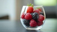 Fresh ripe raspberries, blackberries and strawberry in round glass bowl on light background with soft focus. Natural healthy dessert concept.