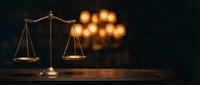 Golden scales of justice on wooden surface with warm bokeh lights creating elegant legal concept for law firm branding and courtroom presentations.