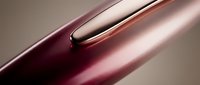 Close-up of luxury cosmetic product with rich burgundy and rose gold metallic finish, showcasing smooth liquid formula for beauty and skincare marketing.