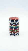 Stack of colorful casino poker chips in red, blue, green, and white arranged vertically on white background for gaming and gambling concepts.