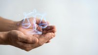 Male hands holding glowing digital justice scales symbol representing legal technology, law firm services, and modern judicial system solutions.