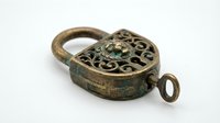 Antique brass padlock with ornate heart-shaped design and decorative scrollwork, featuring aged patina and vintage aesthetic. Suitable for historical projects, antique collections, and heritage designs.
