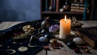 Mystical fortune telling setup with tarot cards, crystals, candle and occult symbols on wooden table for spiritual guidance and divination practices.