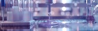 Laboratory glassware and equipment in modern research facility with soft purple lighting, shallow depth of field creates dreamy scientific atmosphere.