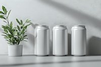 Blank aluminum cans mockup with green plant in pot on white shelf with shadow. Clean minimal product presentation for beverage packaging design.
