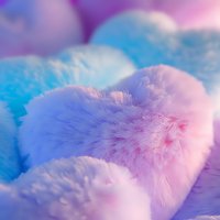 Soft fluffy cotton balls in pastel pink and blue colors with dreamy bokeh effect background creating gentle romantic mood for beauty and spa concepts.