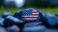 Painted American flag on dark stone against blurred green nature background, patriotic concept representing USA values and national pride.