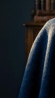 Cozy blue knitted sweater detail in warm home library setting with wooden bookshelf background for autumn winter fashion and lifestyle concepts.