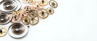 Vintage clockwork mechanism parts with golden gears, springs and metal components arranged on white background for steampunk design projects.