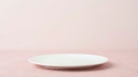 Empty white plate on soft pink textured surface, isolated on neutral background. Suitable for food styling, product mockups, tableware design, and culinary presentations.