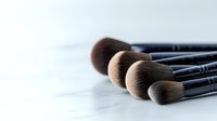 Professional makeup brushes arranged in row on light background, soft focus on bristles shows luxurious texture and quality for cosmetic application and beauty artistry.