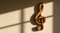 Wooden treble clef music symbol casting shadow on cream wall with natural sunlight streaming through window blinds creating geometric light patterns.