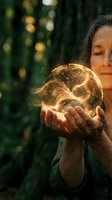 Young woman holding glowing orb with golden light particles in forest setting, representing magic, energy, spirituality, and wonder for fantasy and conceptual designs.