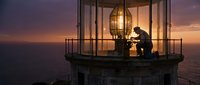 Lighthouse keeper maintaining beacon light at sunset, silhouetted figure working in illuminated lantern room overlooking ocean waters during golden hour twilight.