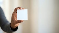 Male hand holding blank white card against neutral background for branding, marketing, and business messaging purposes.