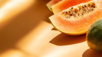 Fresh ripe cantaloupe melon slices with seeds on wooden surface in warm sunlight for healthy eating and summer nutrition concepts.