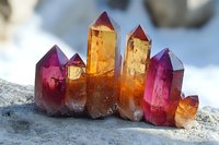 Vibrant pink and amber quartz crystal cluster formation on natural stone background, showcasing geometric mineral growth with translucent prismatic structures in sunlight.