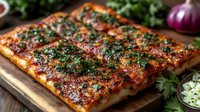 Grilled pork belly slices garnished with fresh herbs and spices on wooden cutting board, crispy skin glistening with marinade, served with chopped garnish.