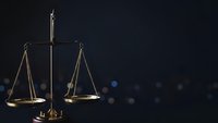 Golden scales of justice on dark background with bokeh lights for legal services and law firm presentations.