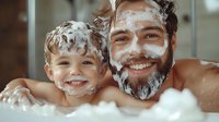 Cheerful father and son having fun during bath time, covered in soap bubbles and foam, sharing joyful moment together. Genuine emotions and bonding experience.