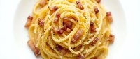 Creamy carbonara pasta with crispy bacon and cheese sauce, isolated on white background for food styling and culinary design projects.