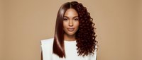 Young African American woman with curly brown hair wearing white top against beige background for beauty and fashion concepts.