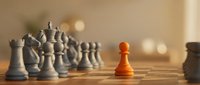 Orange pawn stands out among gray chess pieces on wooden board, symbolizing leadership, uniqueness, and strategic thinking in business concepts.