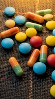 Colorful pills and capsules scattered on textured surface representing healthcare, medicine, pharmaceutical industry, treatment options, and wellness concepts.